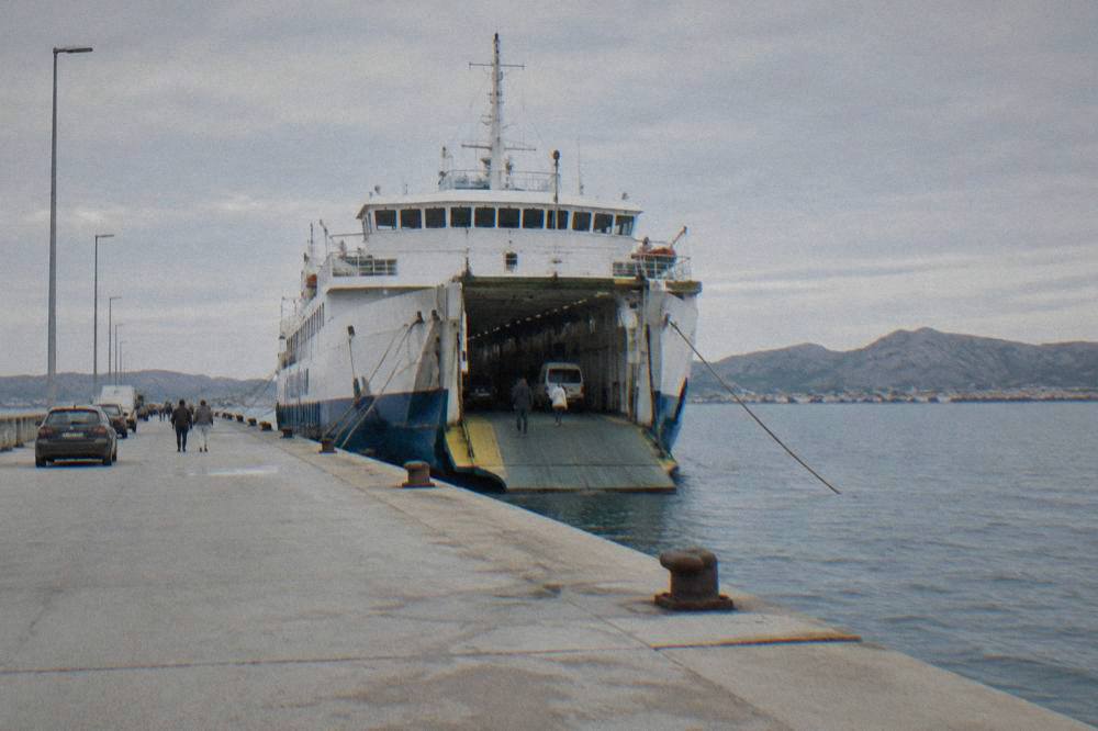 A car ferry moored at the quay in Gaženica port with calm sea and karst hills behind