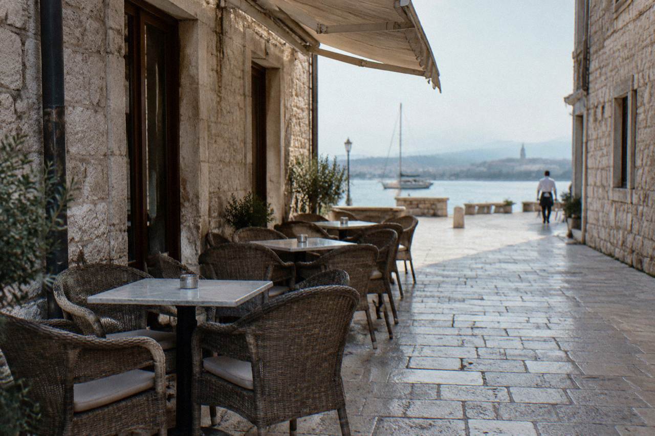 A cafe terrace with empty tables on a pale limestone lane in Zadar Old Town