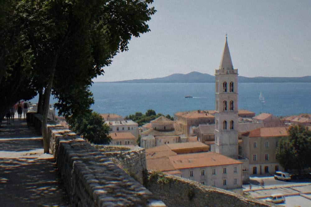 Terracotta roofs and a bell tower of Zadar Old Town with the Adriatic beyond, from a bastion wall