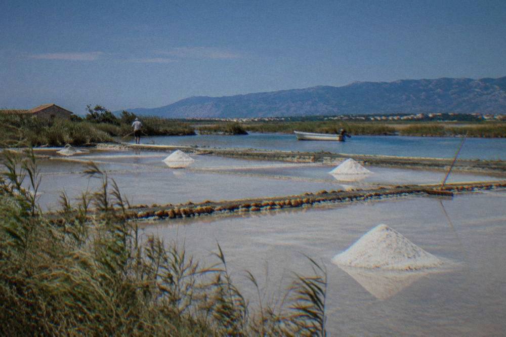 Shallow salt pans near Nin with reeds along the edges and distant hills under a clear sky
