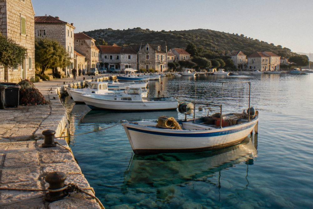 The small harbour of Sali with moored fishing boats and stone houses along a turquoise quay