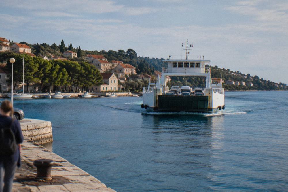 A car ferry approaching the stone quay of Preko on Ugljan across calm blue water