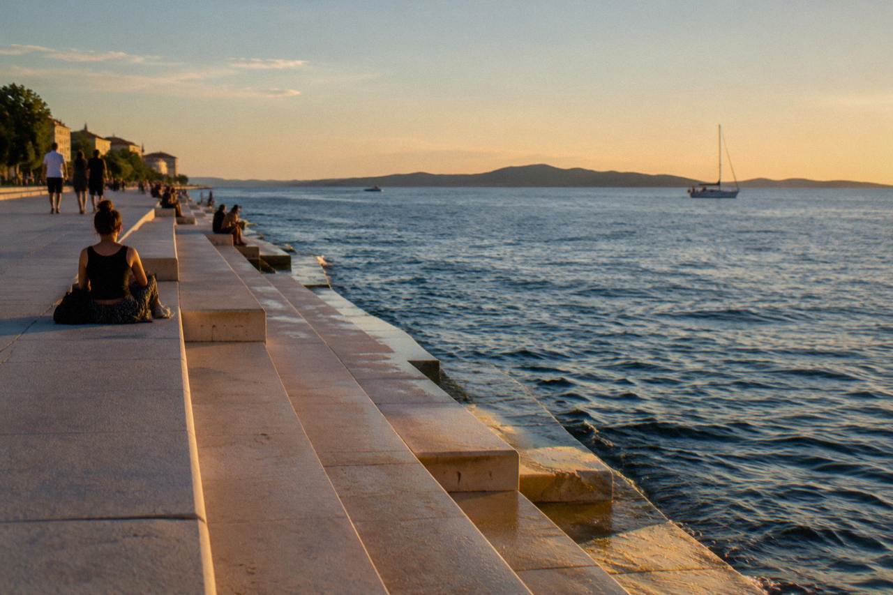 Calm blue Adriatic water beside the stone waterfront promenade near the Sea Organ with an island on the horizon