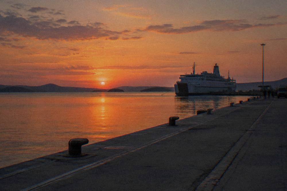 The empty concrete quay at Gaženica at dusk with a large ferry moored in the distance