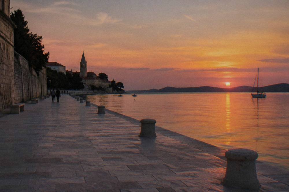 The wide stone waterfront promenade along Zadar's peninsula at dusk with calm sea beside the old town wall