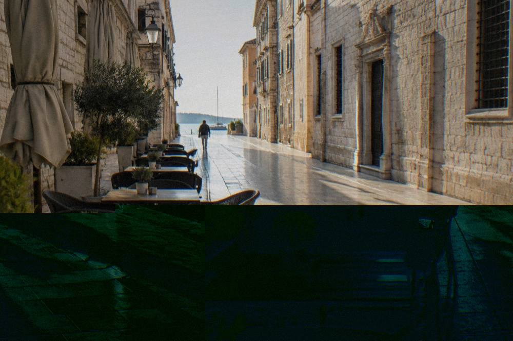 Quiet limestone-paved street in Zadar Old Town with an empty cafe terrace in the morning