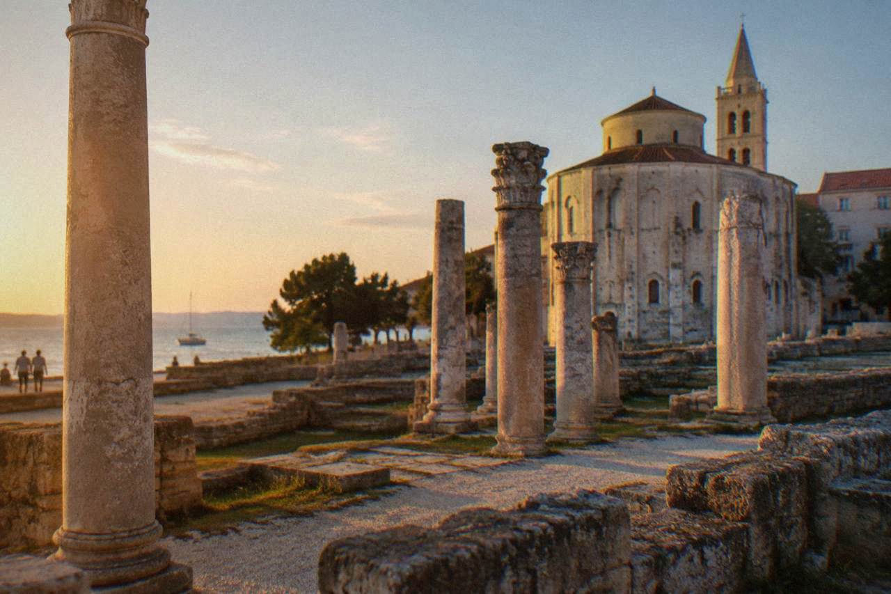 Ancient columns and ruins of the Roman Forum in Zadar with a church behind