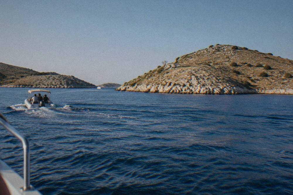 Bare pale limestone Kornati islets rising from calm blue sea on a clear day
