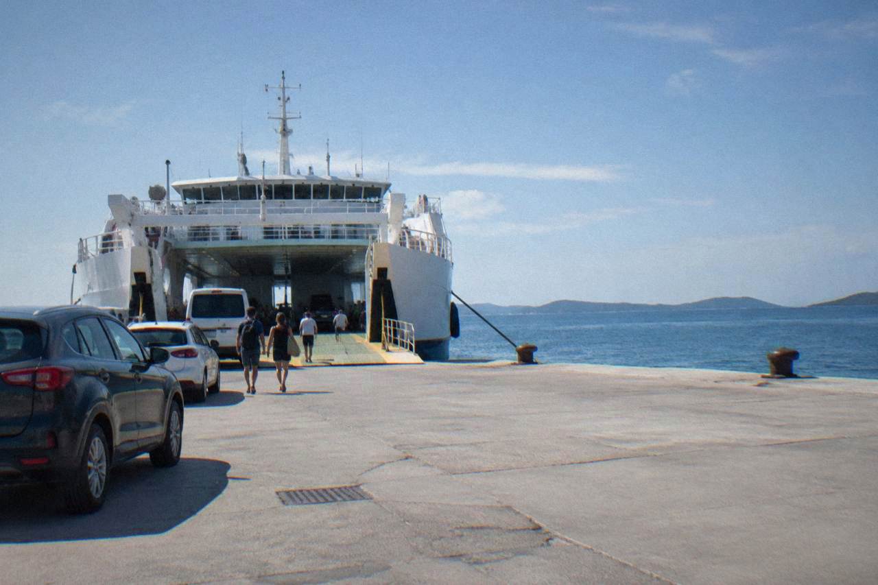 A car ferry at the quay of Gaženica port with calm sea and low islands behind
