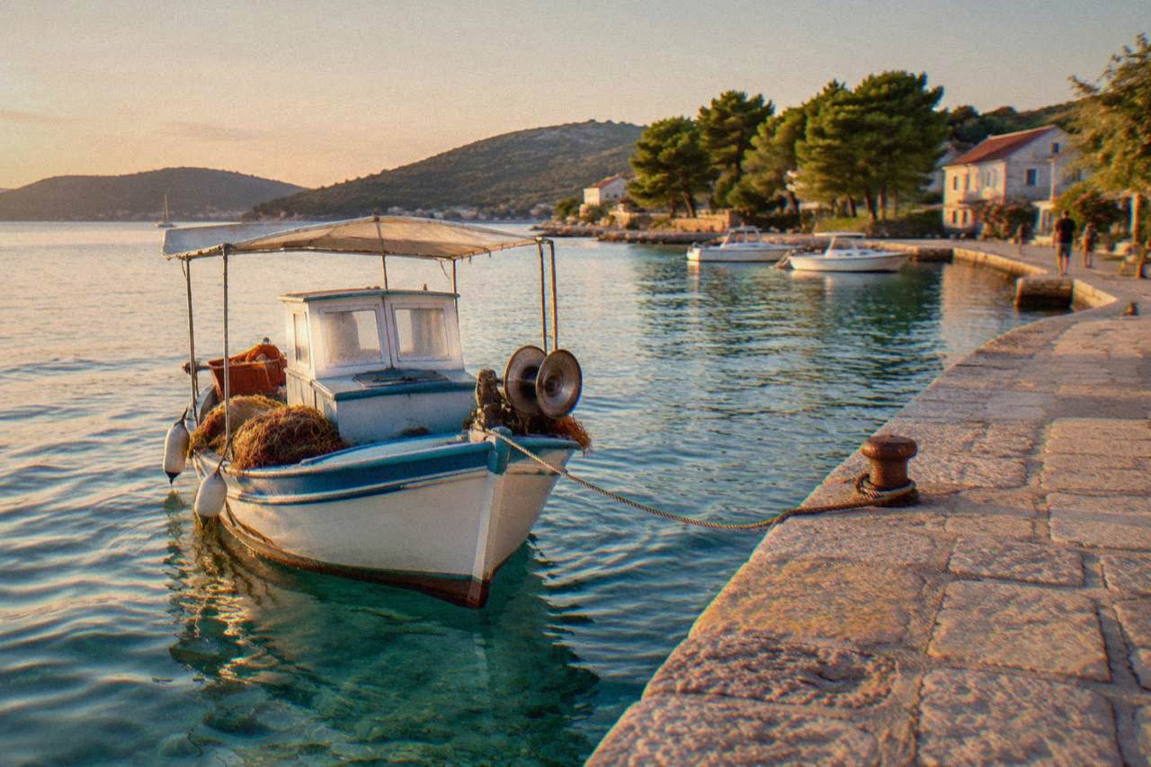 Fishing boat moored in clear turquoise water by a stone quay in Preko on Ugljan