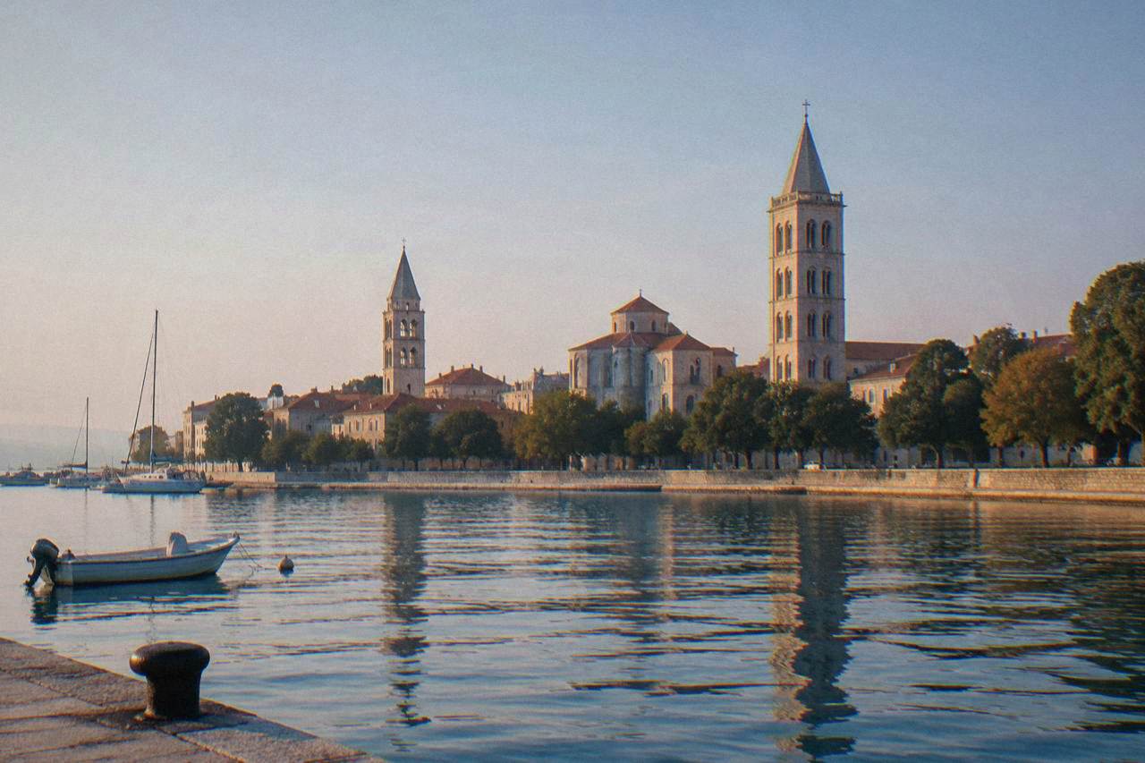 Stone churches and bell tower of Zadar's Old Town across the harbour water in morning light