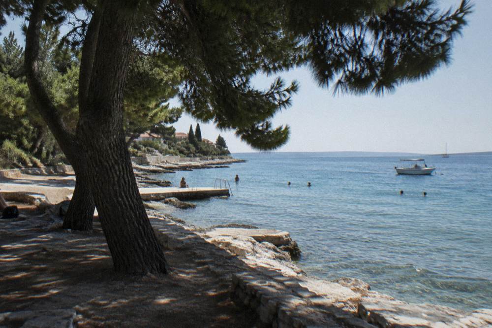 Sunny Arbanasi waterfront with clear sky and distant swimmers in summer light
