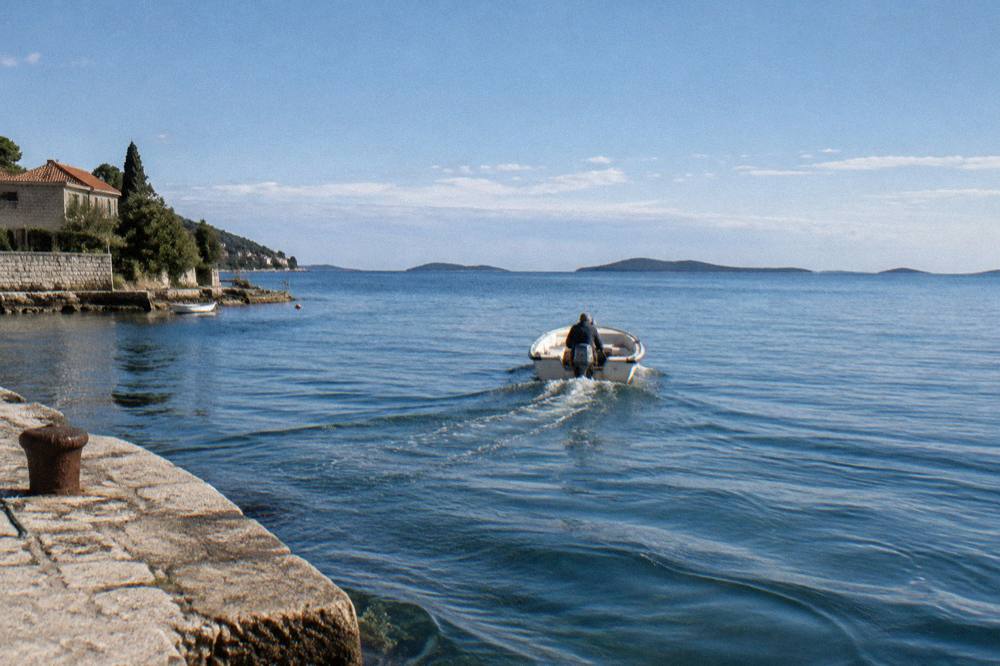 Small boat leaving a stone quay near Arbanasi toward distant islands