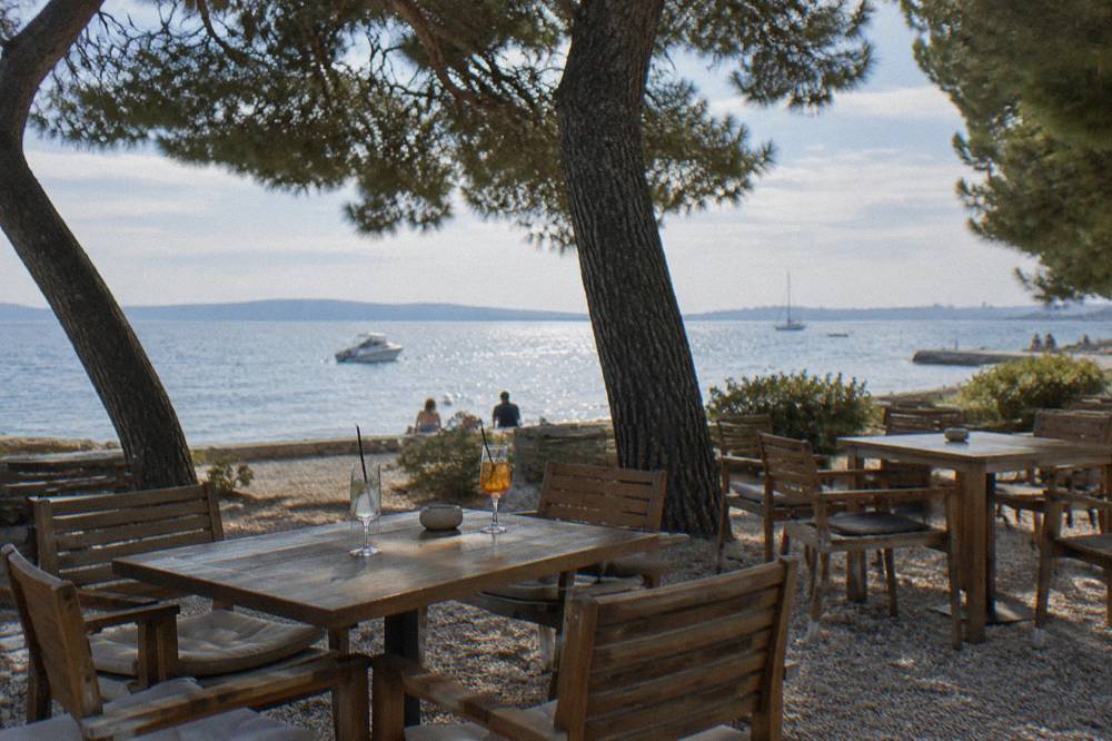 Cafe terrace under pines near the Borik beach with the sea behind