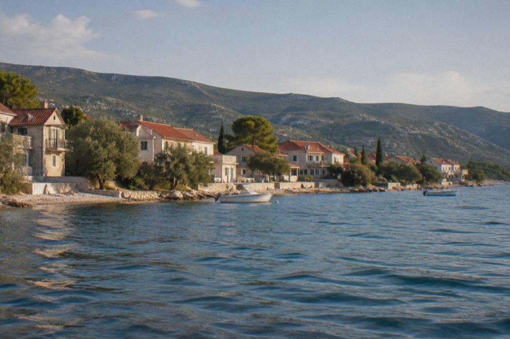Diklo coastline with stone houses seen from the water in soft natural light
