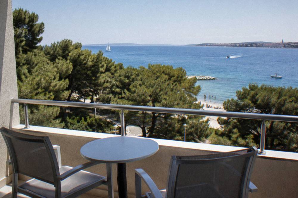 Balcony view over pine tops and sea from a Kolovare hotel room