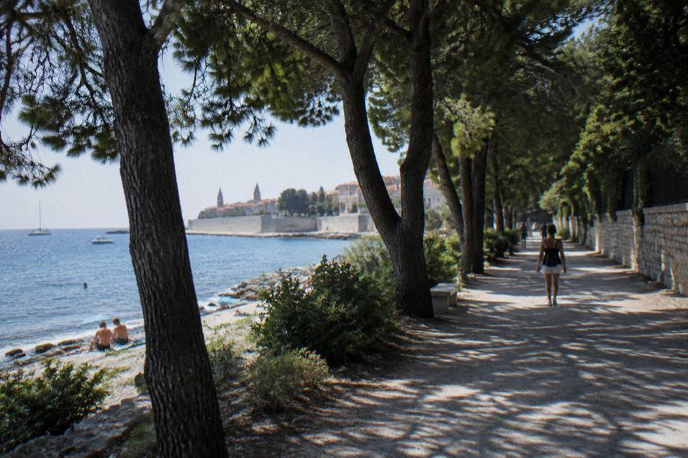 Shaded park path leading from Kolovare toward the Old Town walls