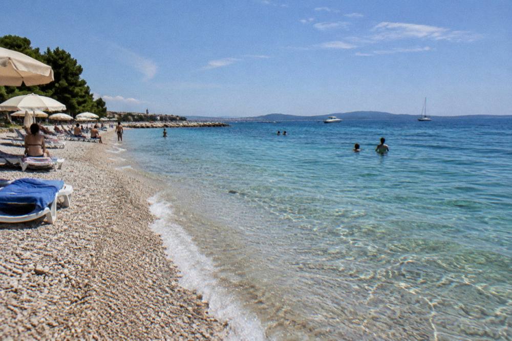 Crescent of fine pebbles and clear shallow water at Kolovare Beach