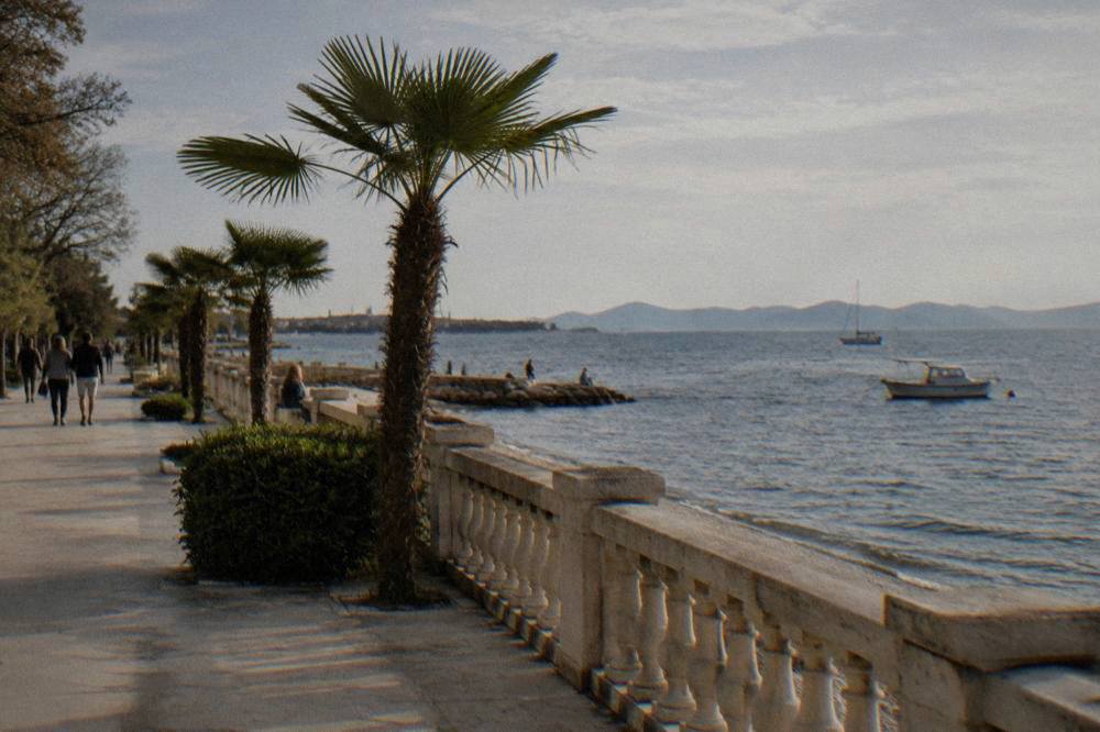 Kolovare sea promenade with palms and a view of distant islands