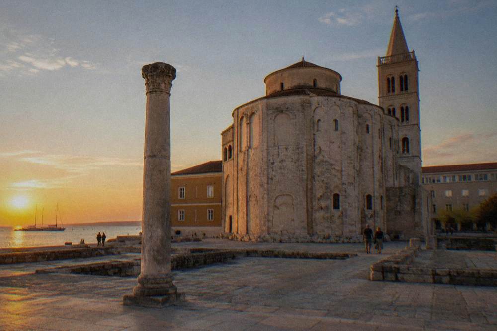 Round pale stone church beside the Roman column in the Old Town