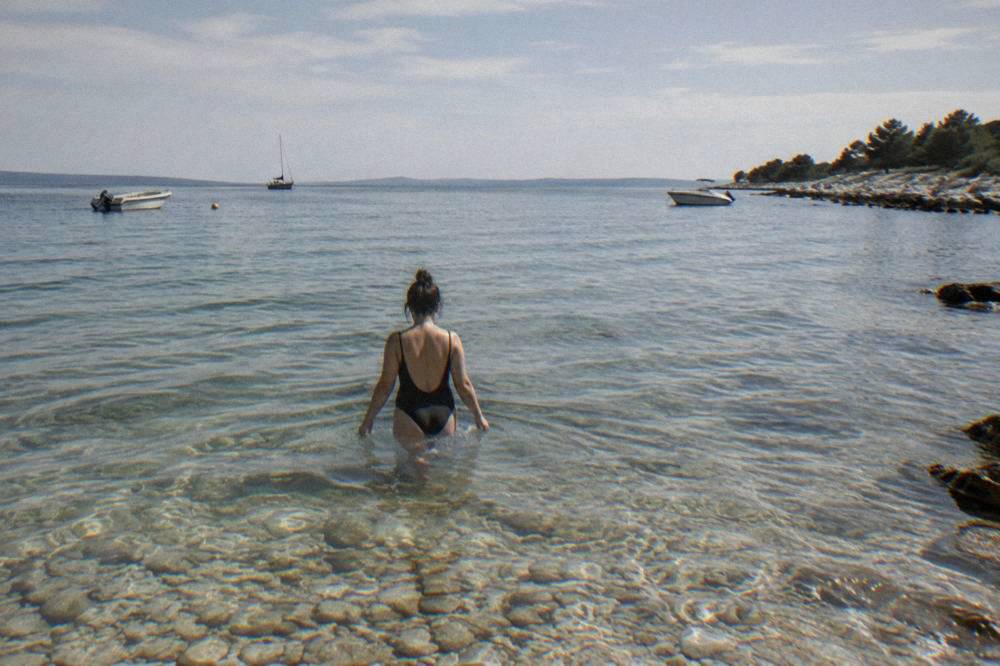 Swimmer wading into transparent shallow water at Puntamika in summer light