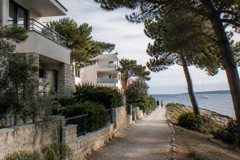Apartment buildings among pines with a footpath to the Puntamika sea