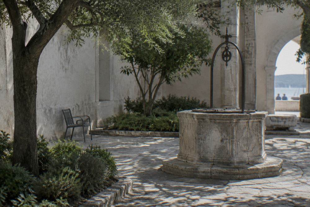 Shaded stone courtyard with a well-head and dappled light in soft natural light