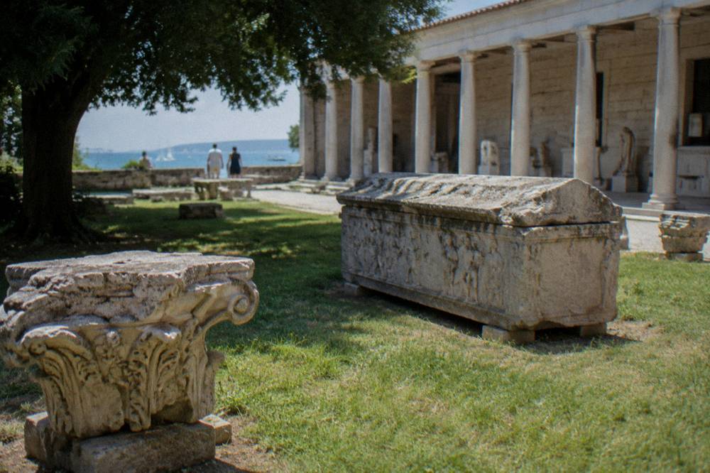 Carved stone fragments and a sarcophagus in a museum courtyard