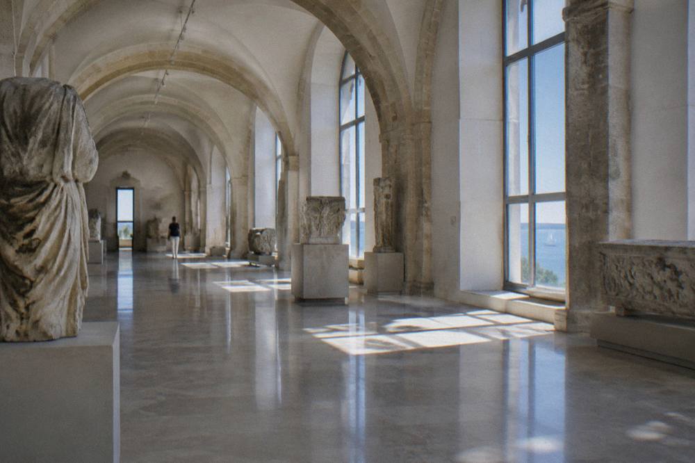 Cool vaulted stone gallery with arches and bright windows in summer light
