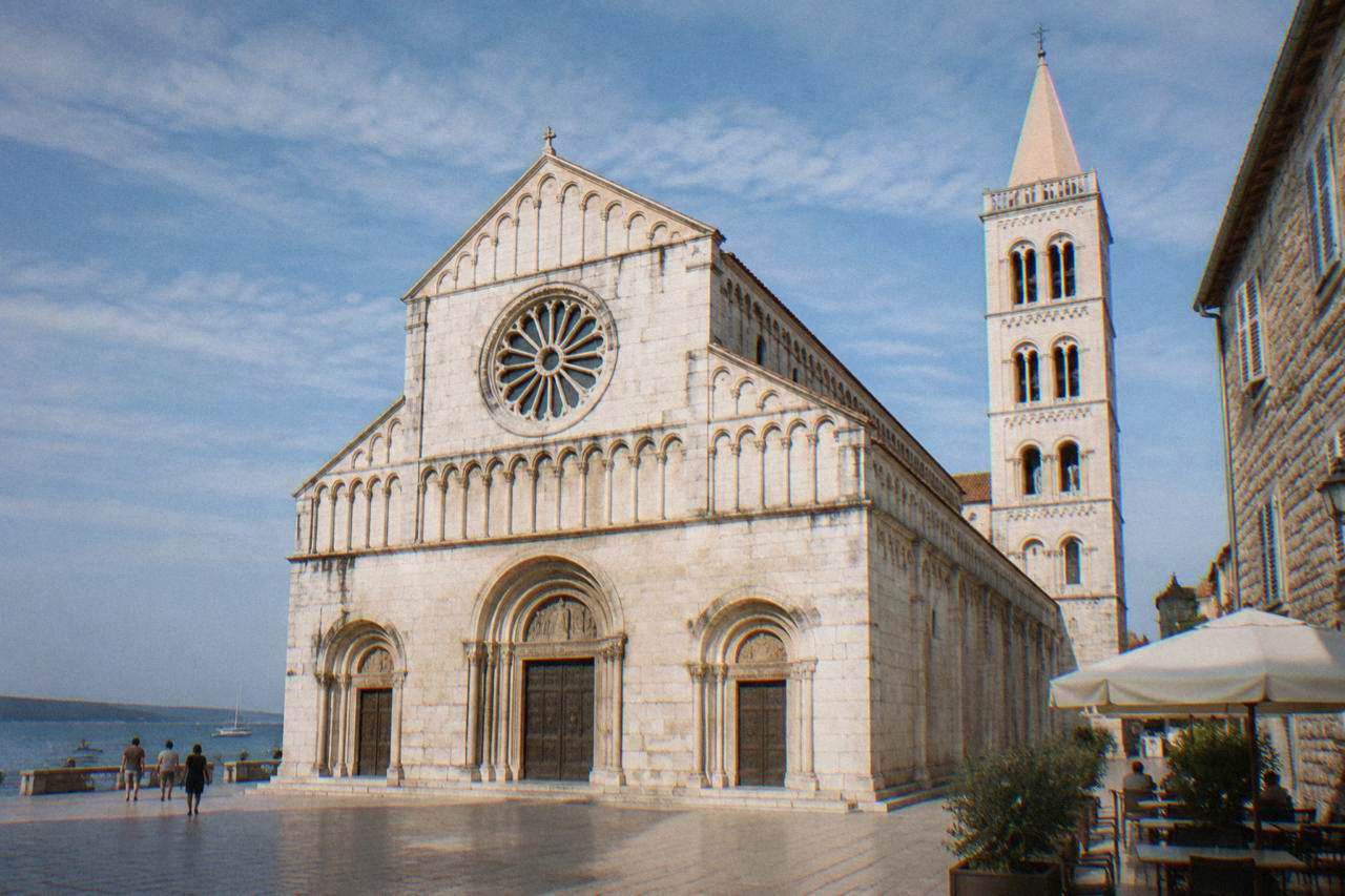 Romanesque cathedral facade with rose window and bell tower on a clear day