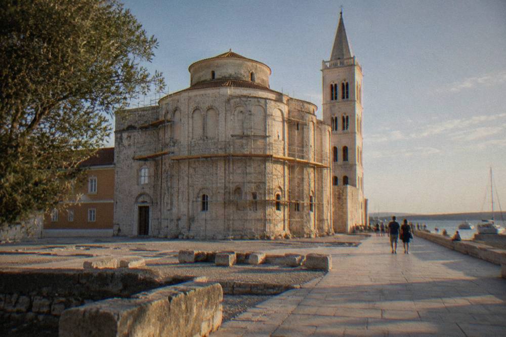 Round stone church partly framed by light scaffolding in the square