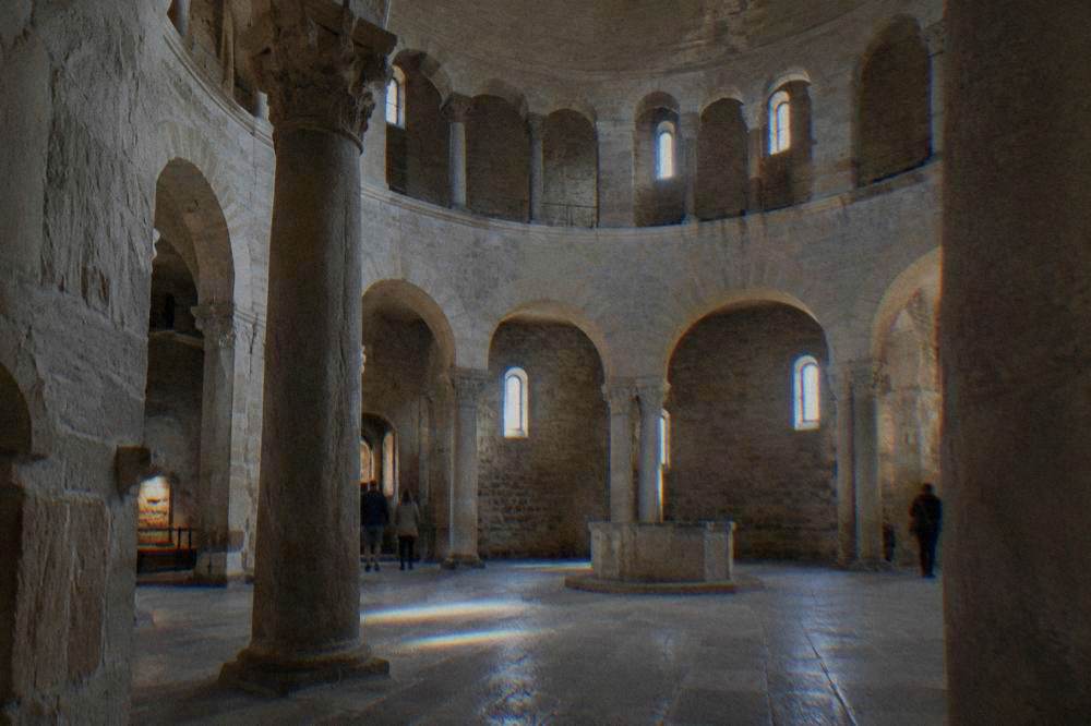 Bare circular stone interior with an upper gallery and soft light