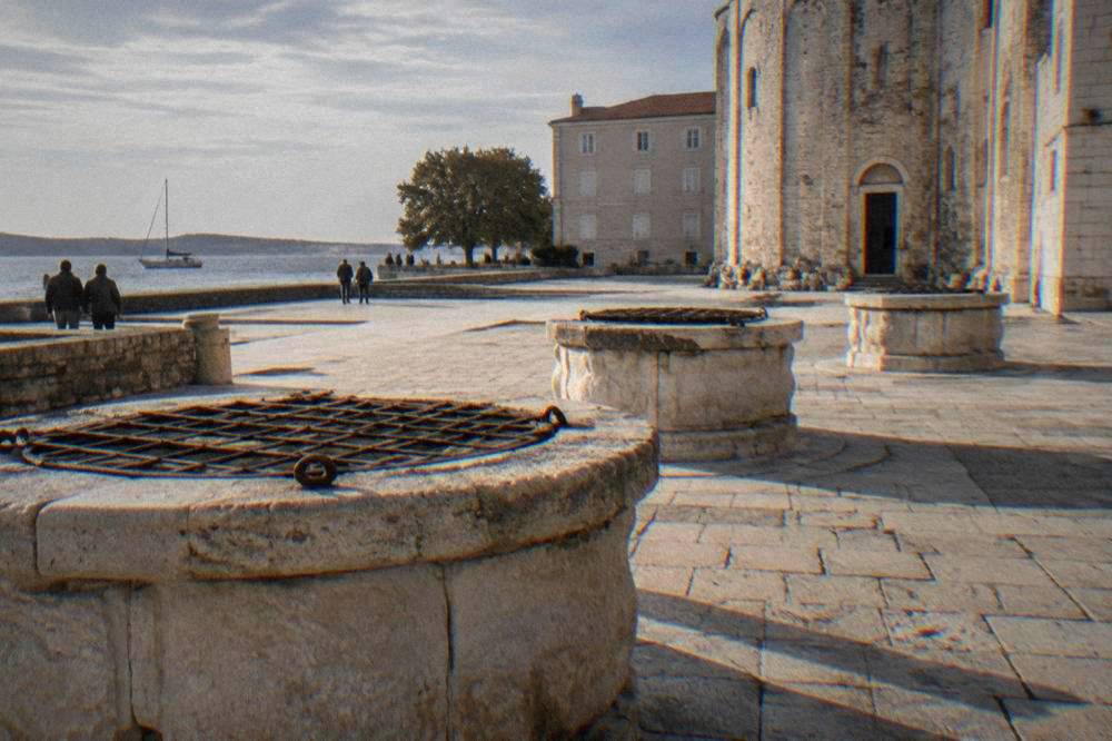 Worn stone well-heads with iron gratings in sunlight in soft natural light