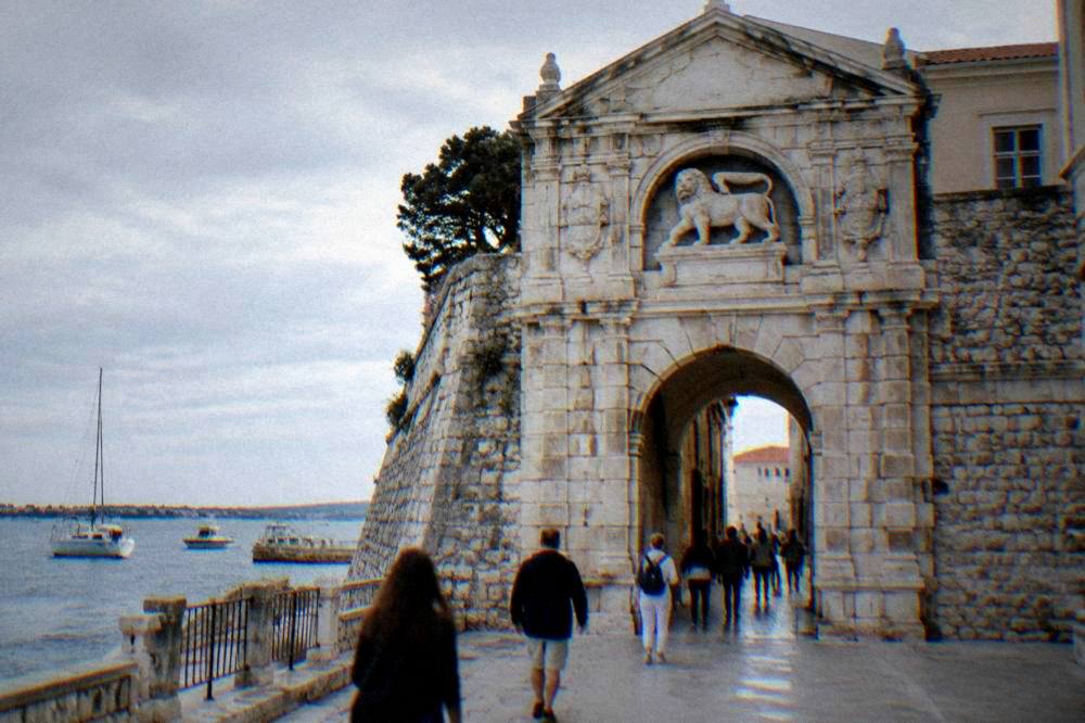 Stone gate arch with sculpted lion at the edge of the Old Town