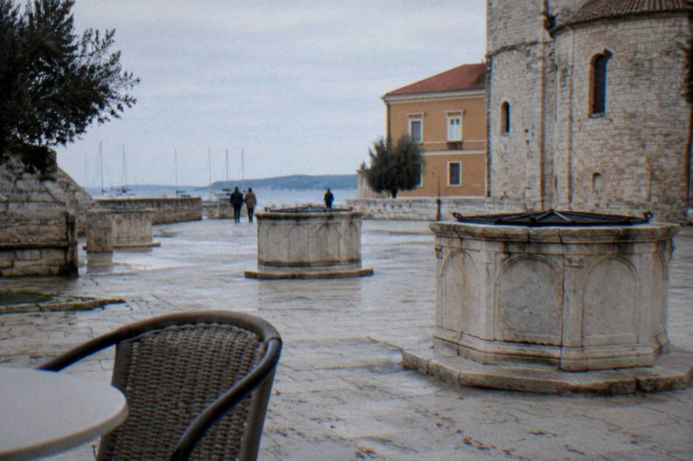 Square in soft overcast light with pale paving and well-heads