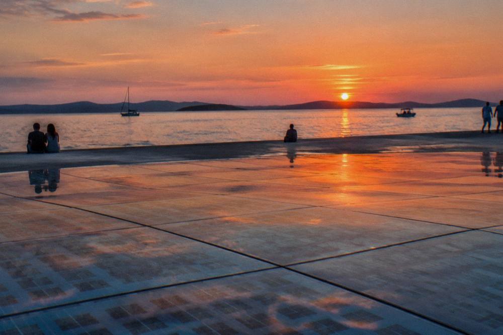 Low view over glass panels toward sunset behind distant islands