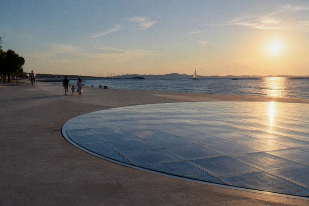 Flat paved waterfront with the glass circle and a distant family