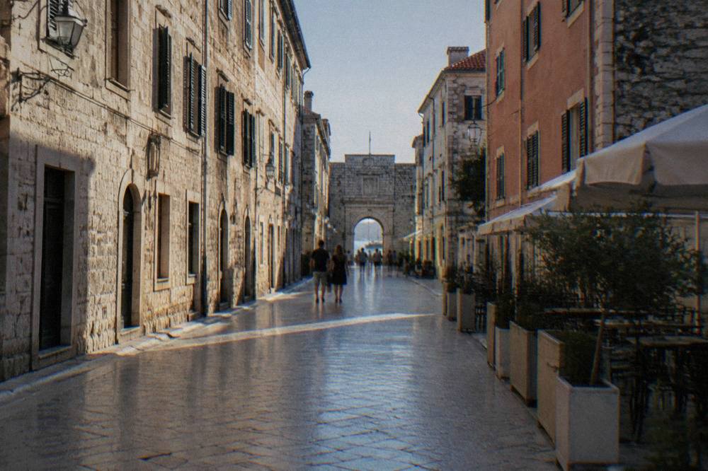 View down the polished stone street toward a distant gate arch
