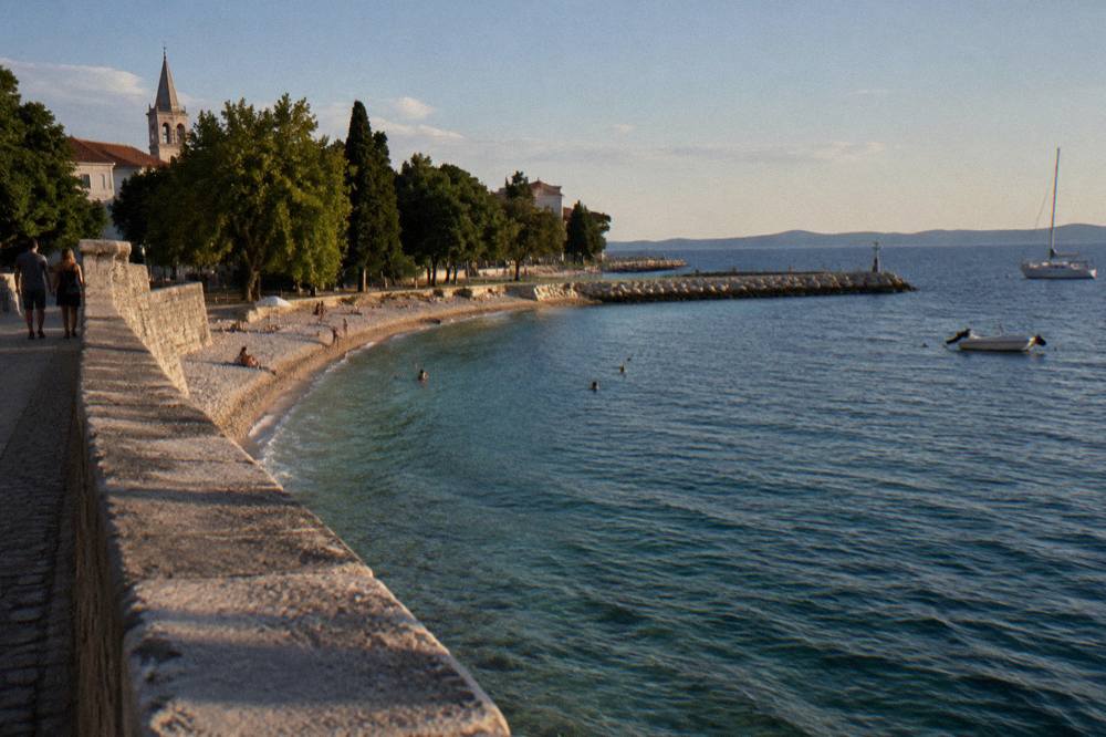 Kolovare shoreline with beach curve and stone breakwater from the sea wall