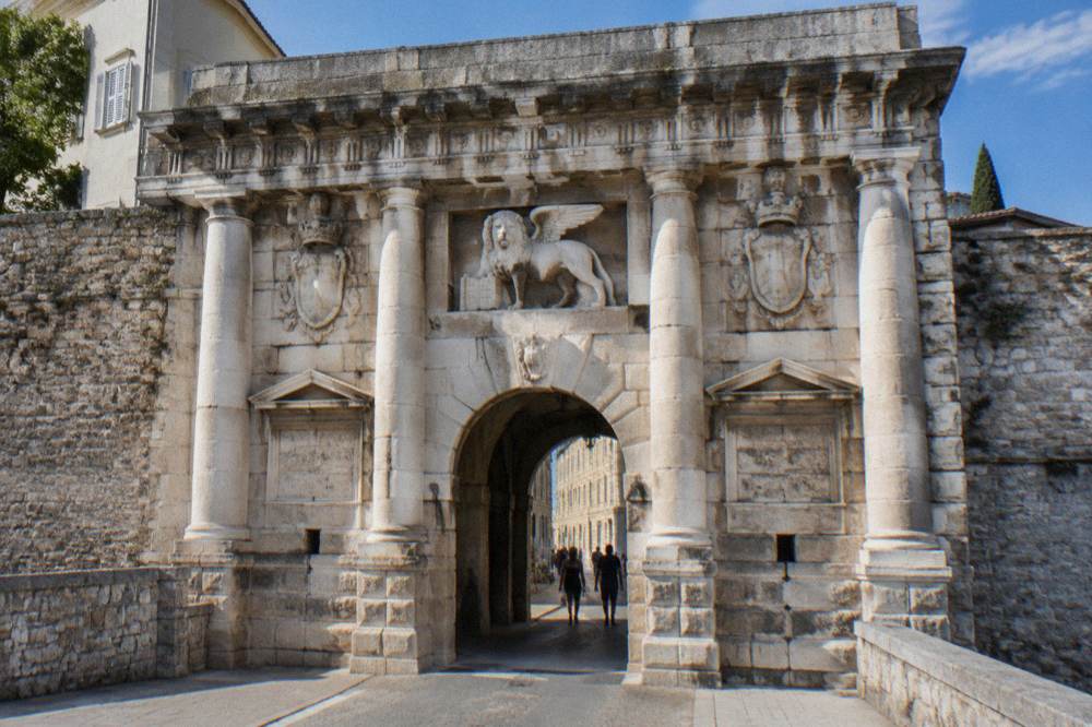 Carved lion relief and stonework above the gate arch on a clear day