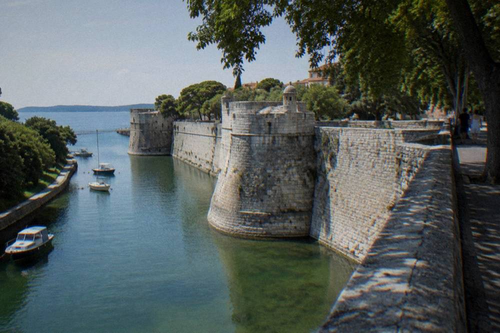 City wall with a green moat and bastion towers in summer light