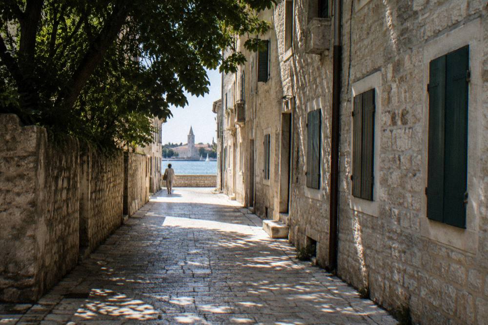 Narrow Old Town lane with deep shade and sunlit limestone
