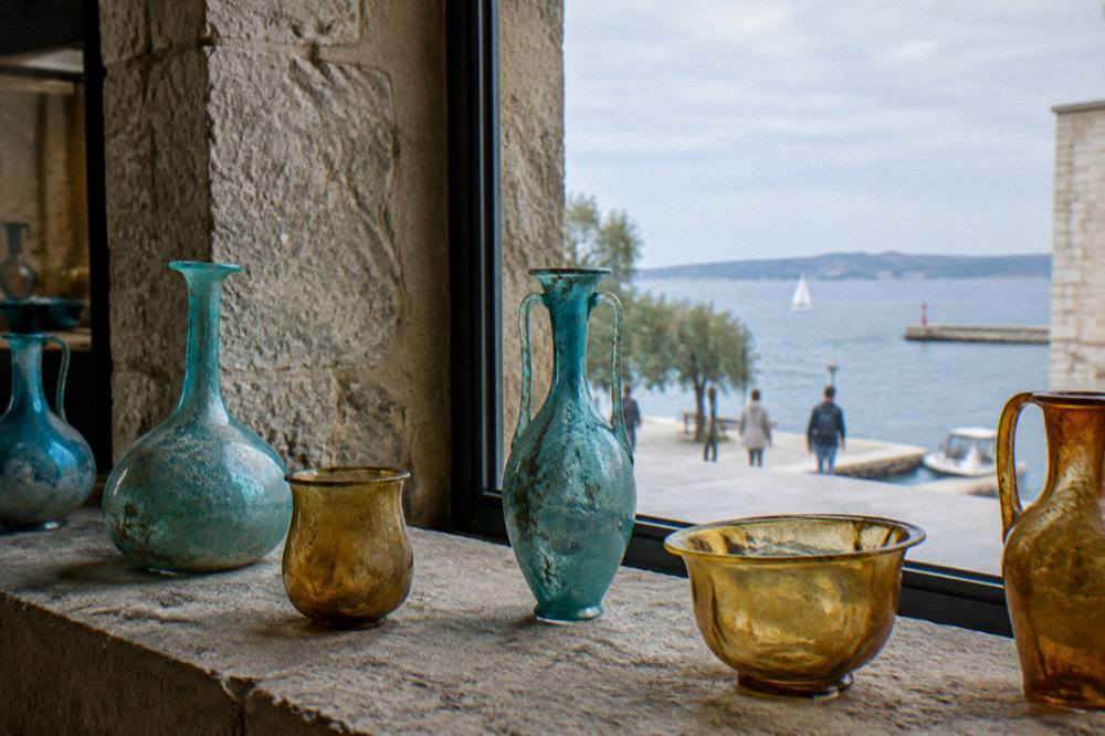 Turquoise and amber glass vessels on a stone ledge in window light