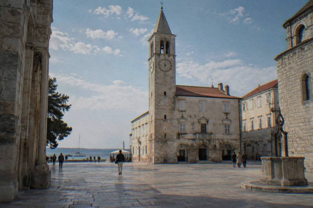 Slender clock tower on a pale stone building above the square