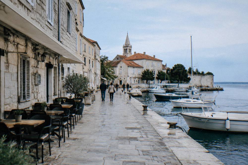 Stone-paved Old Town lane with cafe chairs and a church spire