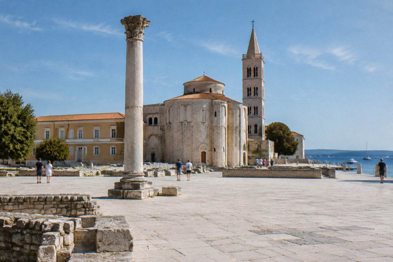 Roman forum paving with a lone standing column and round church behind