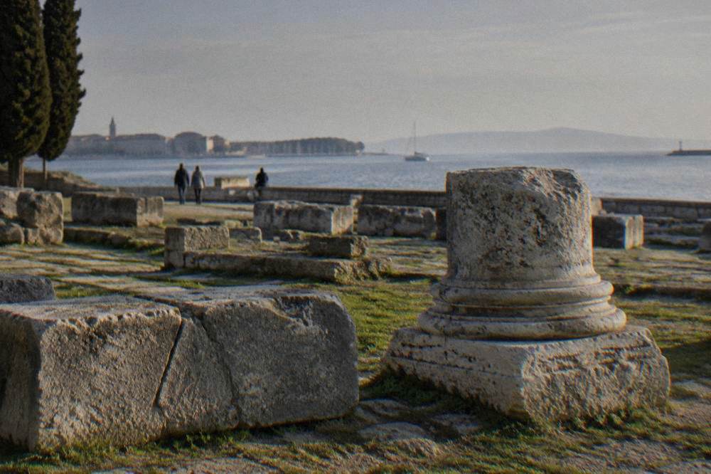 Carved stone blocks and a Roman column base in the forum