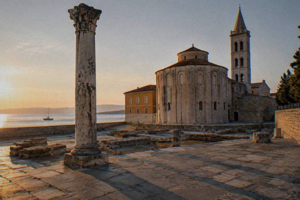 Long shadows over ancient forum paving and column at sunrise