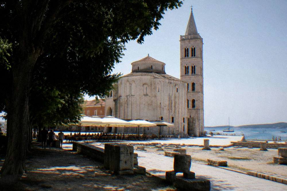 Round stone church at the edge of the forum beside a cafe awning