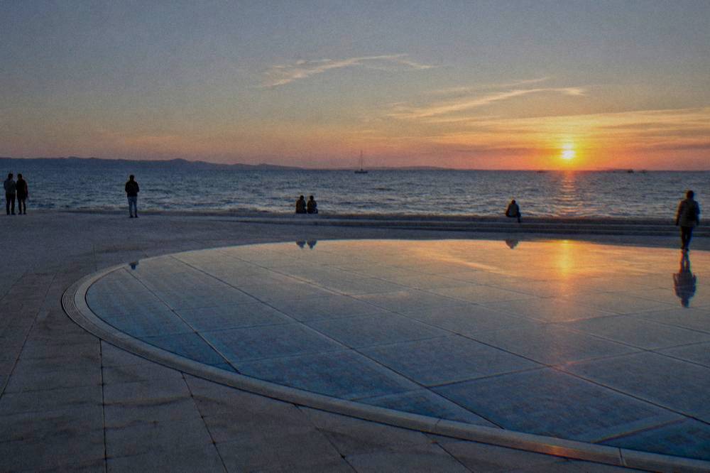 Glass-panel circle next to the sea steps at an orange dusk
